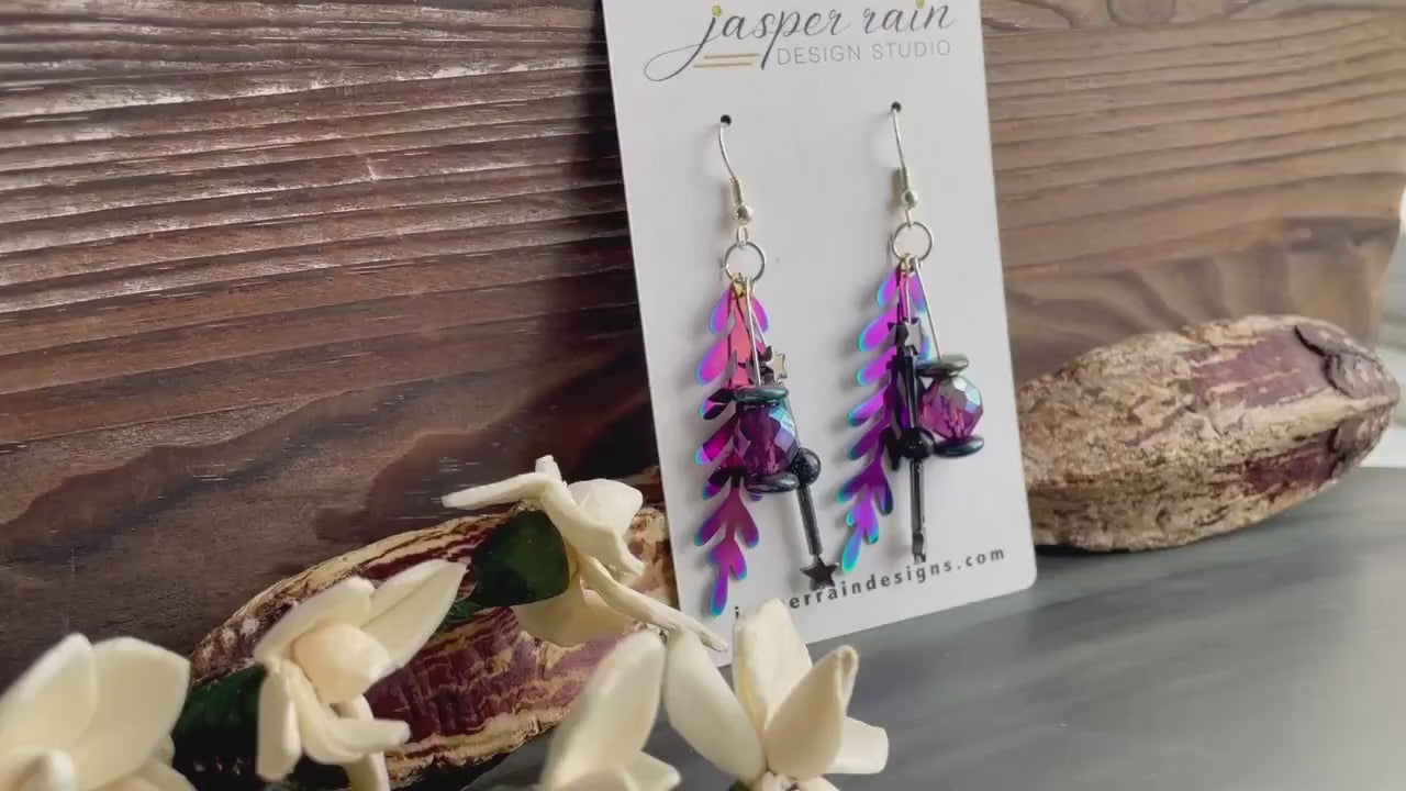 Colorful rainbow dangle earrings that are handmade and feature hematite stone stars and a metal rainbow leaf