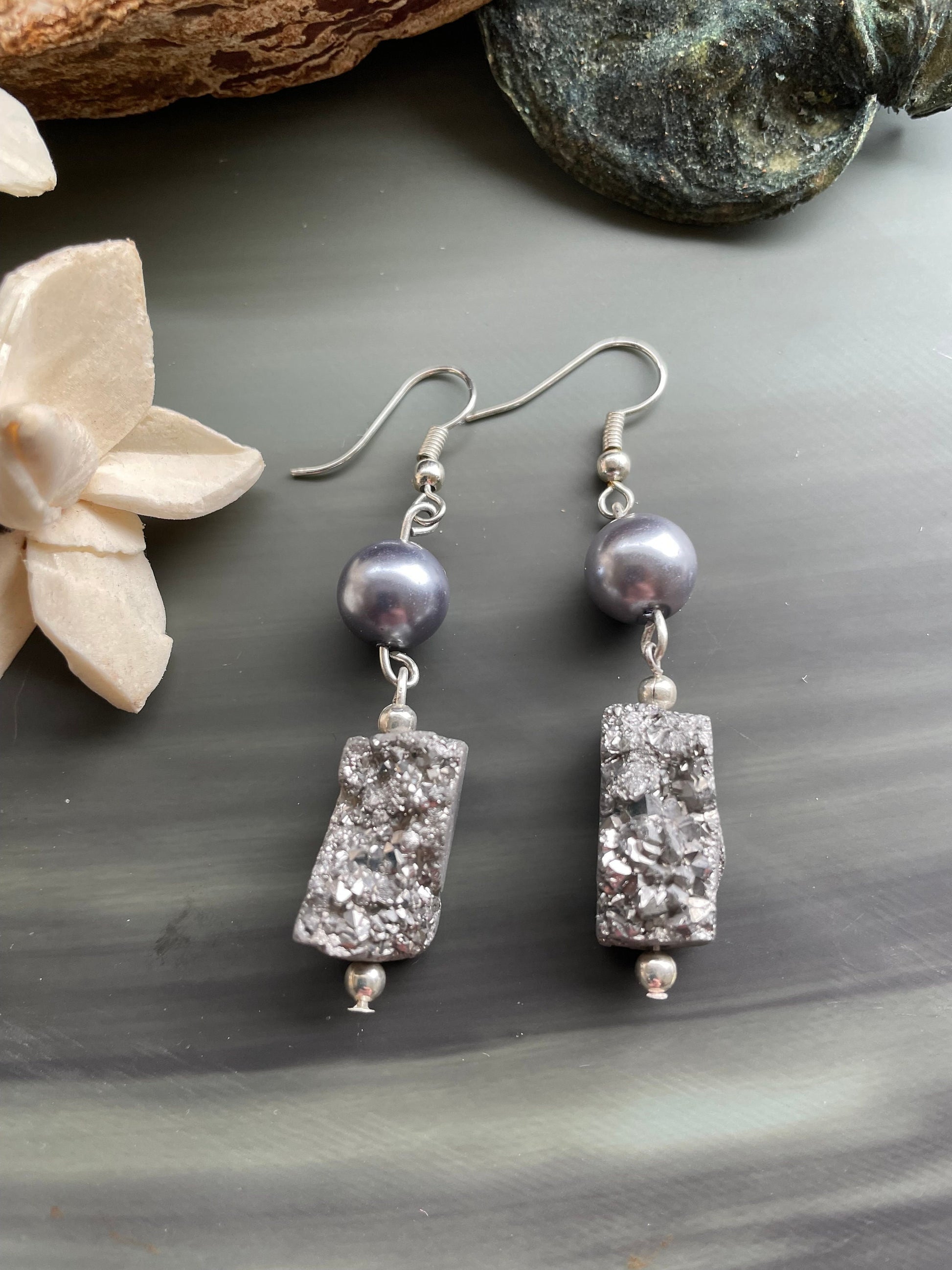 Platinum Druzy earrings with silver round pearl beads. They are sitting on a stone tablet. They are  hand made