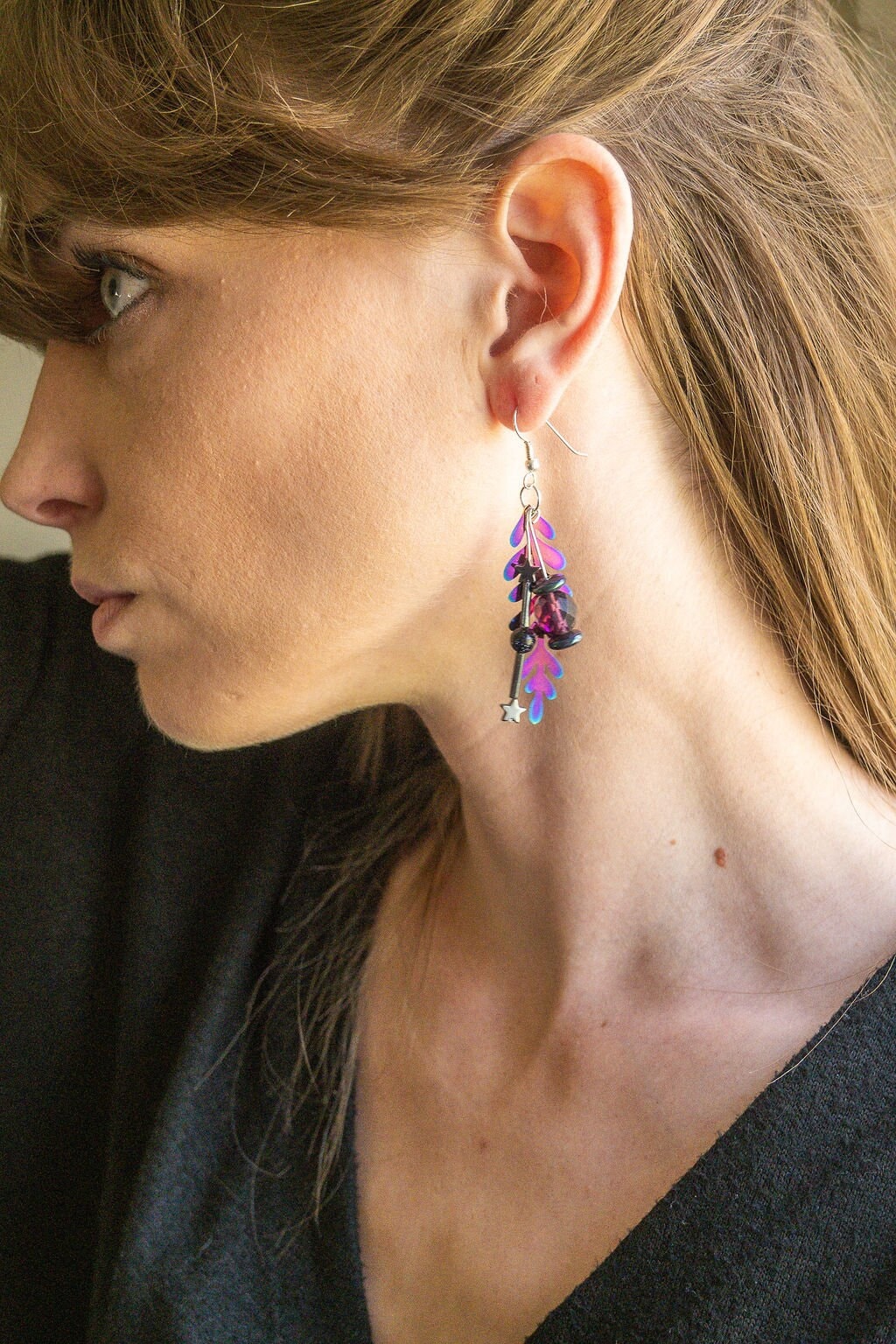 Colorful rainbow dangle earrings that are handmade and feature hematite stone stars and a metal rainbow leaf