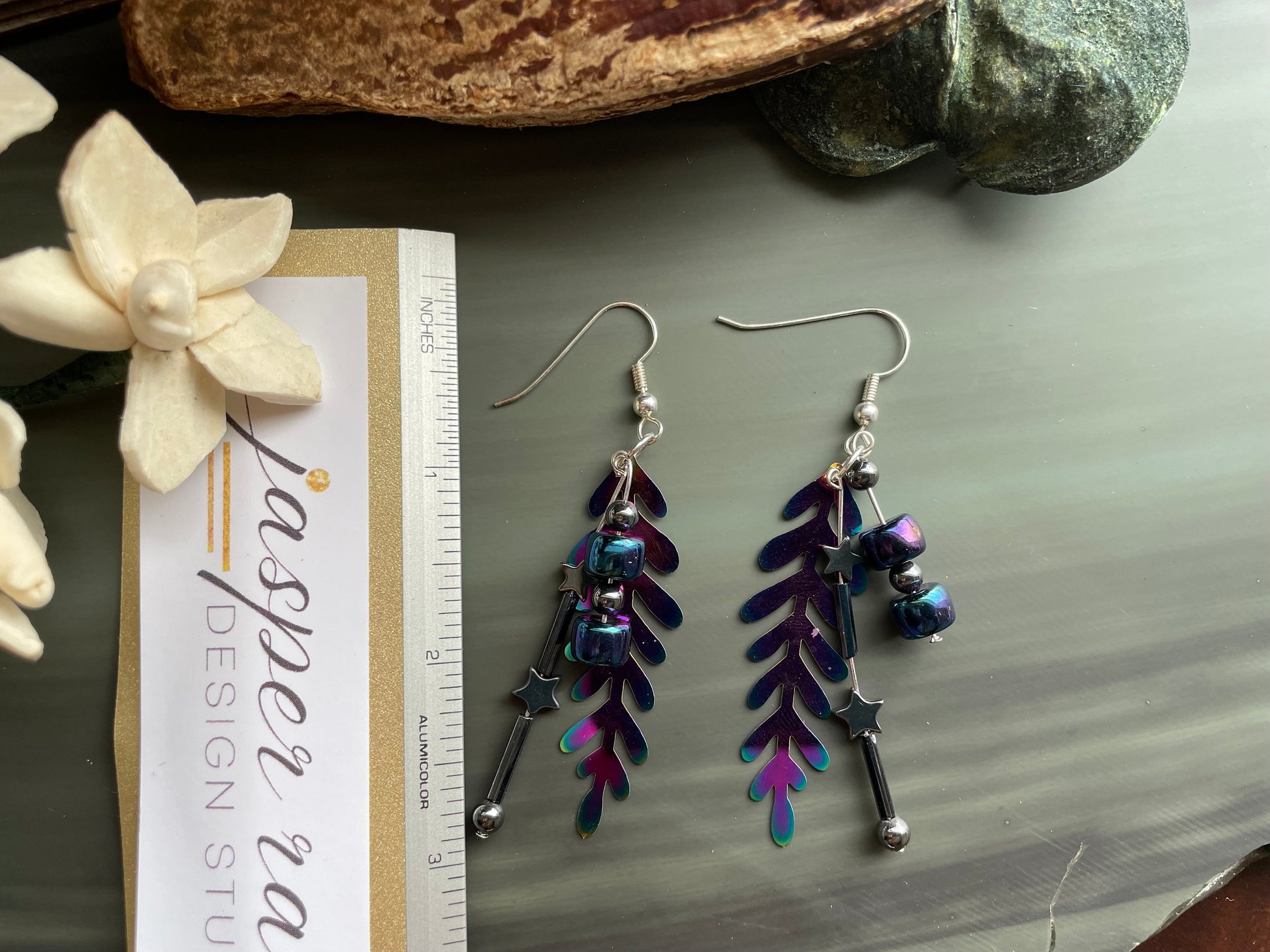 Colorful rainbow dangle earrings that are handmade and feature hematite stone stars and a metal rainbow leaf