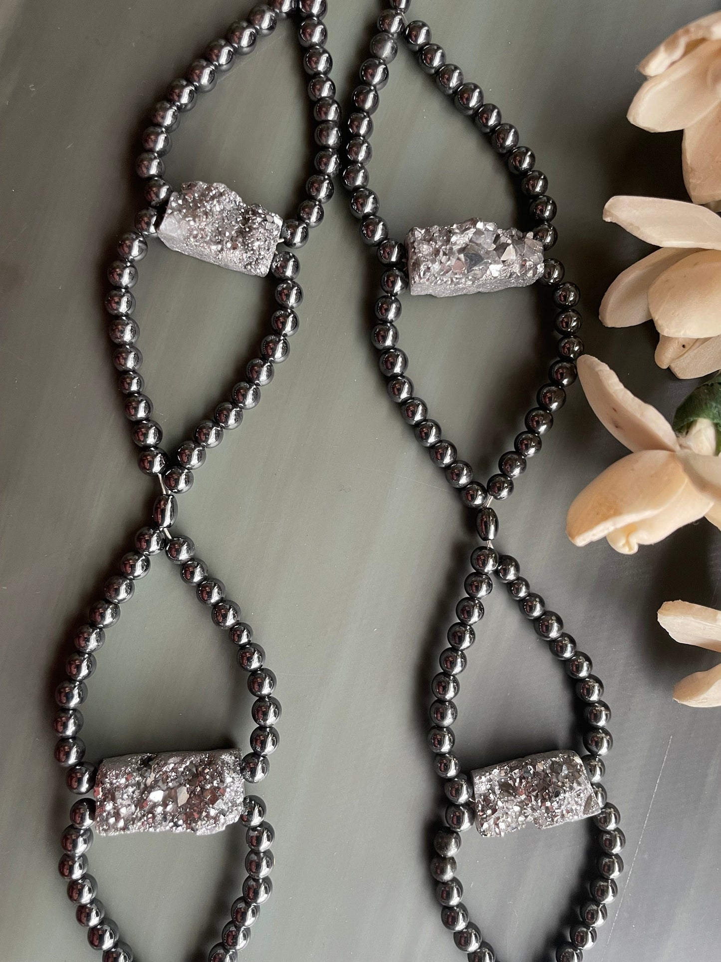 Platinum Druzy and Hematite long length necklace sitting on a stone tablet.